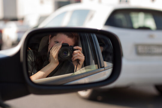 a woman takes a picture of herself in the car mirror