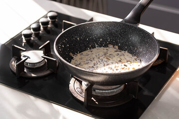 Close up of professional Chef cook hands roasts champignons mushrooms with cream in wok pan for Mediterranean cuisine. 