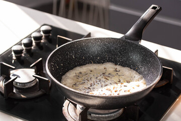 Close up of professional Chef cook hands roasts champignons mushrooms with cream in wok pan for Mediterranean cuisine. 