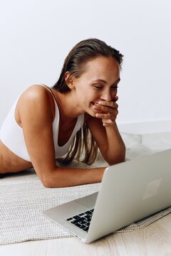 Woman working at home with laptop freelancer working at home trading online lying on the floor and smiling with teeth