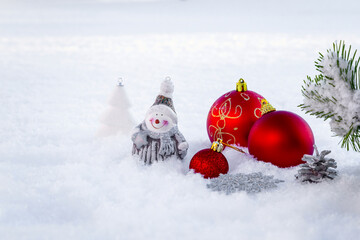 Red Christmas decorations under a fir tree on white snow.