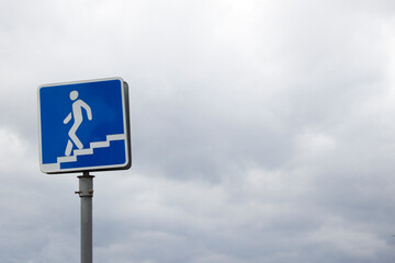 Warning blue road sign of an underground passage at the street with the sky in the background on the daytime.
