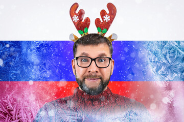 cheerful bearded man is citizen of Russia in funny Christmas reindeer horns on background of frozen flag of Russia