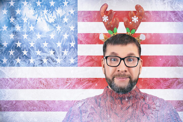 cheerful bearded man with funny deer horns on his head on background of frozen flag of America, crisis with natural gas in winter in new year, increase in energy prices, toned image