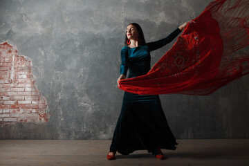 Young adult spanish woman dancing flamenco on gray vintage studio background