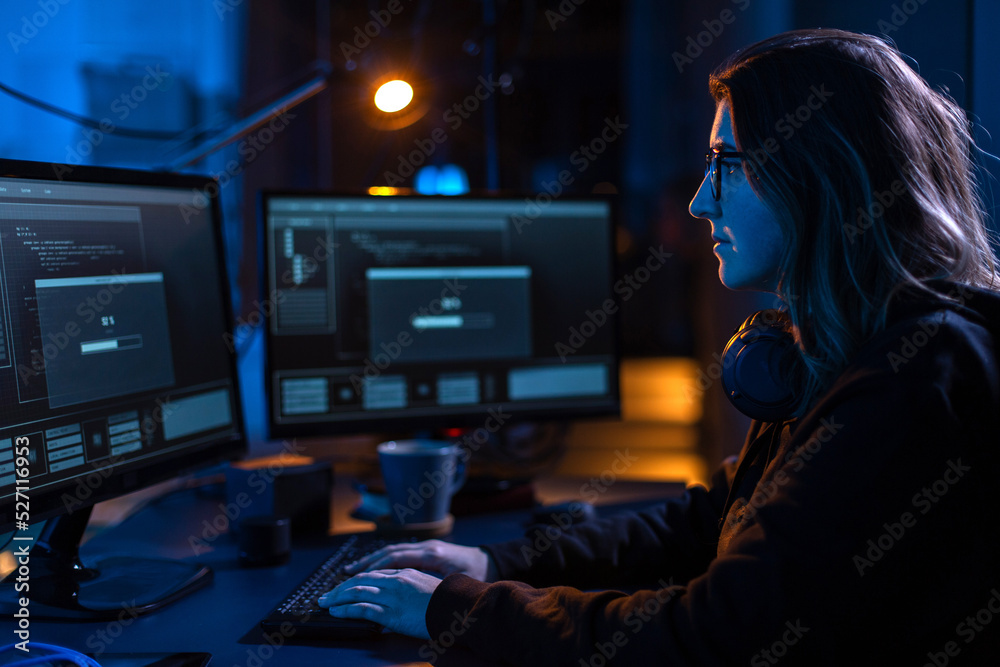 Poster cybercrime, hacking and technology concept - female hacker in dark room writing code or using comput
