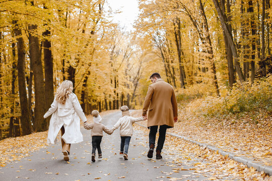 Backside photo of young family on a walk in autumn forest