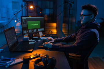 cybercrime, hacking and technology concept - male hacker in dark room writing code or using...