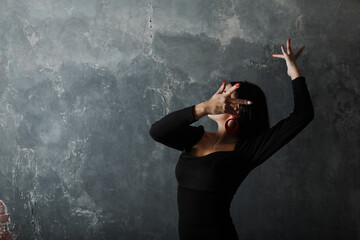 Obraz na płótnie Canvas Young adult spanish woman dancing flamenco on gray vintage studio background
