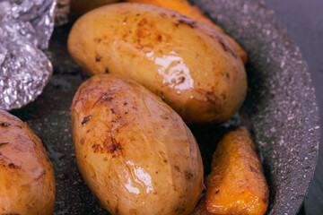 Close-up of appetizing oven baked whole potatoes and carrots served on gray plate. Excellent image for homemade food banners and advertisements.	