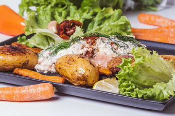 Close-up of appetizing oven baked potatoes and baked salmon in foil. Served on gray plate. Excellent image for homemade food banners and advertisements.