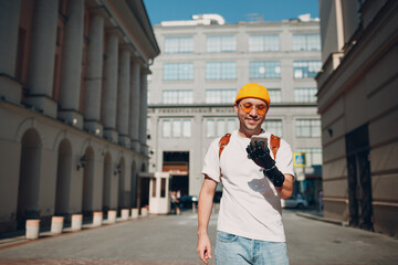 Young disabled man tourist using mobile phone with artificial prosthetic hand and walking at sunny...