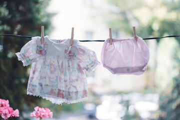 Pink baby dress hanging on a rope in the summer