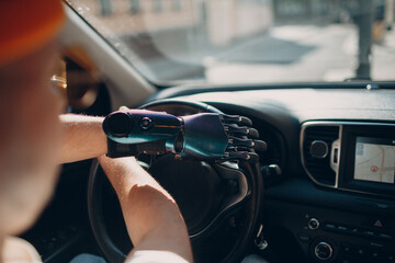 Young disabled man driver with artificial prosthetic hand driving vehicle car. Hands on steering...