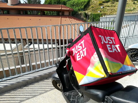 Rome, Italy - June 12, 2019: Typical square container of the JUST EAT home delivery company on a scooter in the sun. Founded in Denmark in 2000 by Jesper Buch, it operates in 13 countries worldwide