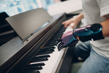 Young disabled man play on piano electronic synthesizer with artificial prosthetic hand in music shop - obrazy, fototapety, plakaty