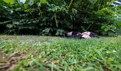 sexy, young, woman lies dead outdoors in grass under a bush, after accident or crime