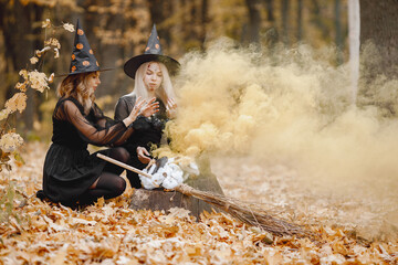 Two witches in forest on Halloween make magic potion