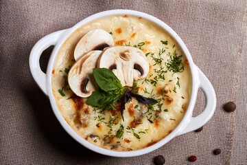 Chicken julienne with cheese, mushrooms and herbs in white plate on wooden board