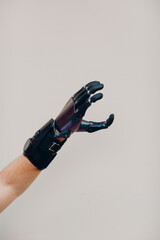 Disabled man with artificial prosthetic hand close up male hand against gray background