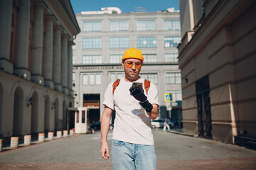 Young disabled man tourist using mobile phone with artificial prosthetic hand and walking at sunny city street outdoor - obrazy, fototapety, plakaty