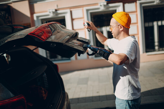 Young Disabled Man With Artificial Prosthetic Hand Closing Back Trunk Of Car Vehicle