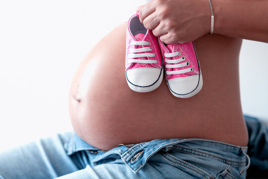 Pregnant Woman with baby shoes, close-up of belly