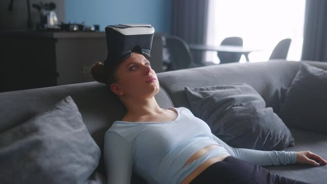 Robot like futuristic doll woman in virtual reality googles interface on head enters metaverse immersive expirience via headset. Creepy looking satisfaction girl in depression after cyber space.