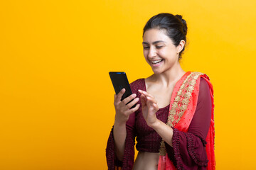 Portrait of young adult indian woman in sari message text sms with mobile phone.