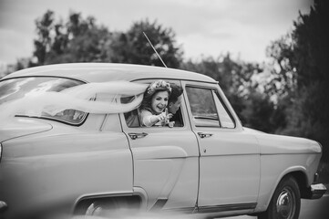 Happy bride and groom, newlywed wedding couple is driving a retro car on a country road for honeymoon after the ceremony. Way. The best day and marriage. Just married. Black and white photo.