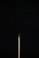 A match with green head on a black background.