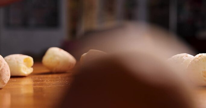 Brazilian cheese bread balls being thrown on a wooden table in slow motion