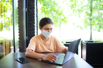 Indian business woman working on her laptop outdoor with mobile phone and face mask - Powered by Adobe