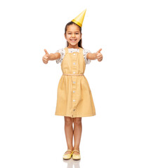 birthday, childhood and people concept - portrait of smiling little girl in dress and party hat showing thumbs up over white background