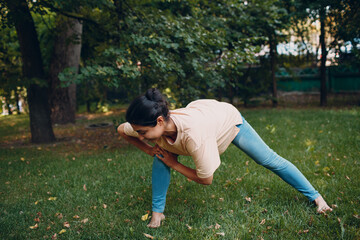 Sporty Millennial Indian Woman in Casual Clothing Stretching Before Training In Park, Doing Warming Up Exercises.