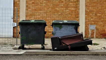 Fototapeta na wymiar sidewalk with rubbish bins and abandoned sofa