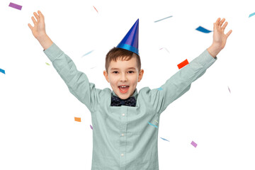 birthday, childhood and people concept - portrait of happy little boy in party hat having fun with confetti over white background