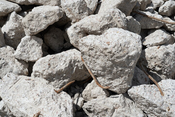 A close-up of many gray pieces of a demolished concrete wall thrown in a mess. The texture of the...