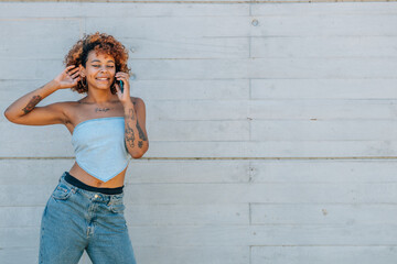 latin african american girl with tattoos and mobile phone in the street outdoors