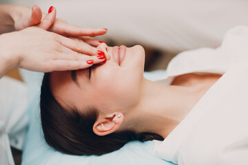 Beautiful young woman getting face treatment massage at beauty spa