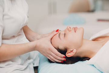 Fototapeta na wymiar Beautiful young woman getting face treatment massage at beauty spa