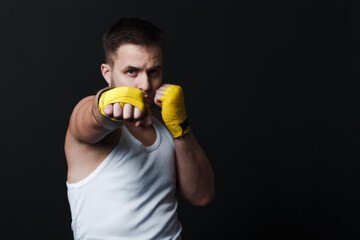Sportsman man boxer stance hits jab at black background.