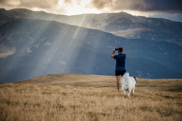 man and dog trekking in high mountains