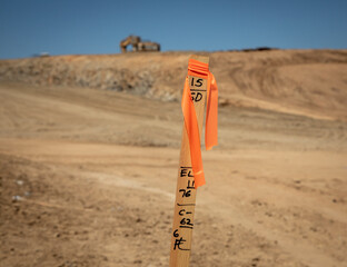 Construction grading stake with construction equipment in background