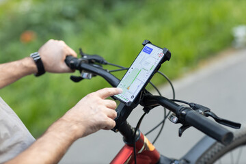 Man planning route using GPS navigation application in mobile phone on his bicycle bike