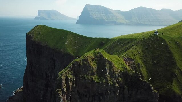 Aerial view of Kalsoy island, Faroe Islands. Amazing Faroese nature, green hills and beautiful rocky cliffs and mountains. Kallur lighthouse. Sunny day in summer. Movie Island in Faroe. 4k footage