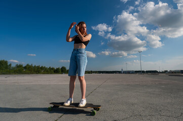 Young caucasian woman riding a longboard outdoors. 