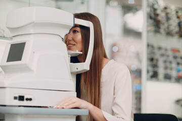 Professional woman doctor using eye testing electronic digital modern equipment checking vision.