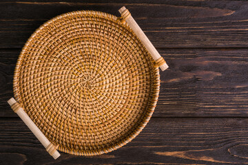 Wicker plate made of straw on a wooden background. view from above - 527135180