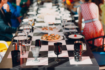 Wedding table decor like a chessboard with black and white dishes glasses with food.